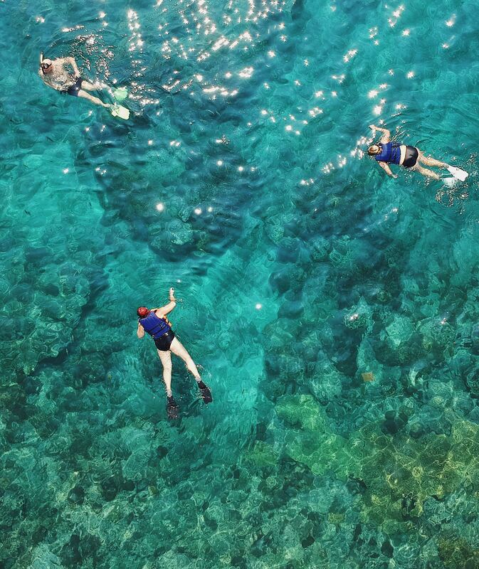 Three people snorkeling in the crystal clear waters of Gozo.Picture