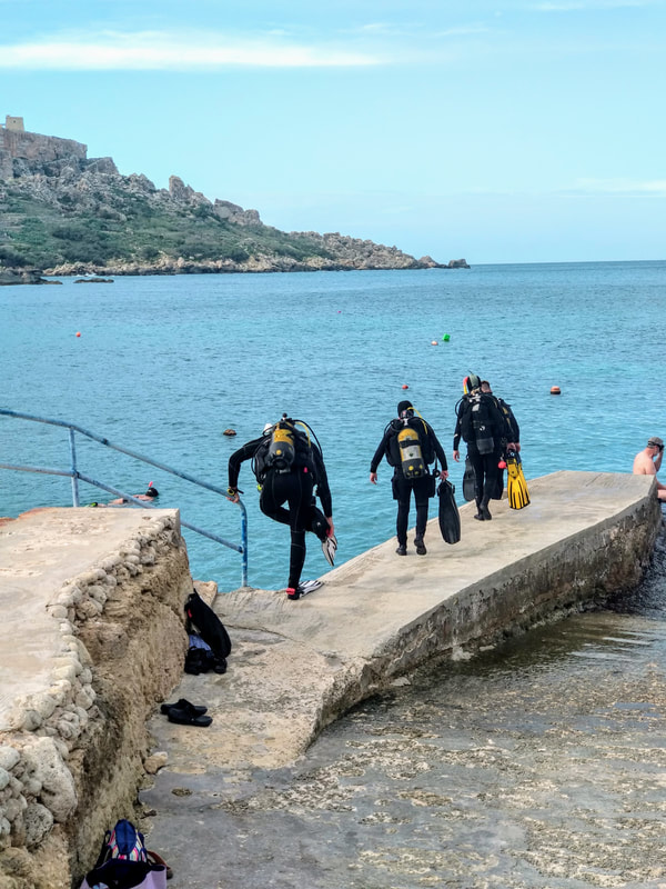 Divers preparing to enter the water for a diving experience on Gozo, Malta.